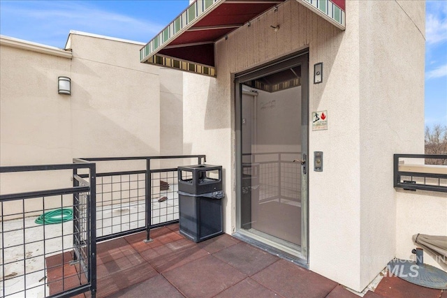 entrance to property featuring a balcony and stucco siding