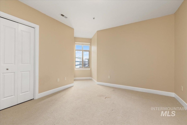 unfurnished bedroom with carpet floors, a closet, visible vents, and baseboards