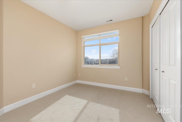 bedroom featuring baseboards, visible vents, a closet, and light colored carpet