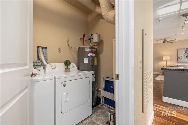 clothes washing area featuring laundry area, baseboards, wood finished floors, independent washer and dryer, and electric water heater