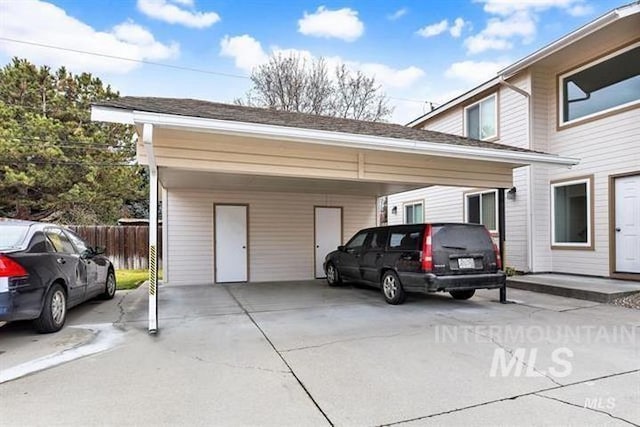 view of parking featuring a carport, fence, and driveway