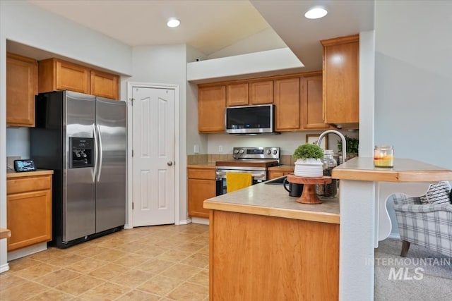 80 Cobblestone Ct, Middleton, ID 83644 - kitchen featuring appliances with stainless steel finishes, a peninsula, light countertops, brown cabinets, and recessed lighting