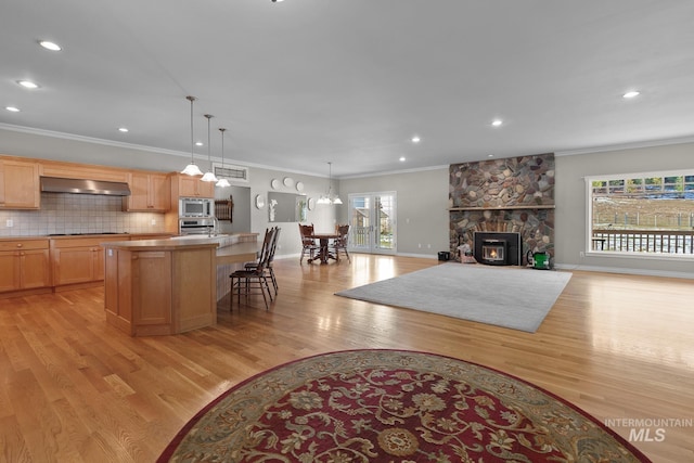 828 W Fork Eagle Creek Rd, Wallace, ID 83873 - kitchen with stainless steel microwave, range hood, oven, light wood finished floors, and a center island