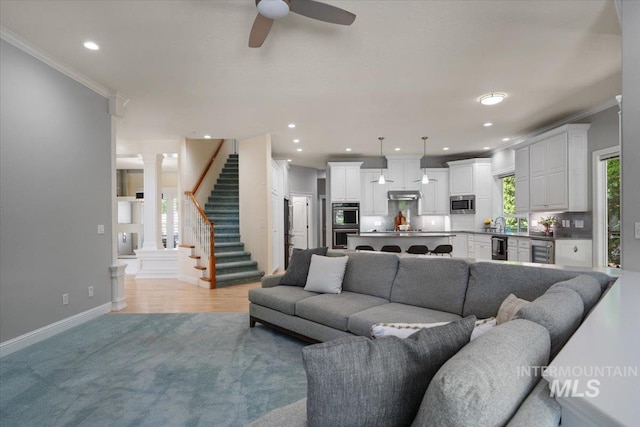 living area with ornamental molding, beverage cooler, ornate columns, ceiling fan, and baseboards