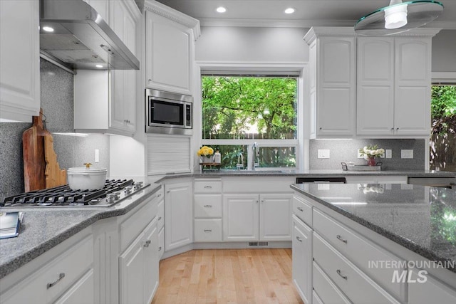 kitchen featuring wall chimney exhaust hood, a sink, stainless steel appliances, backsplash, and recessed lighting