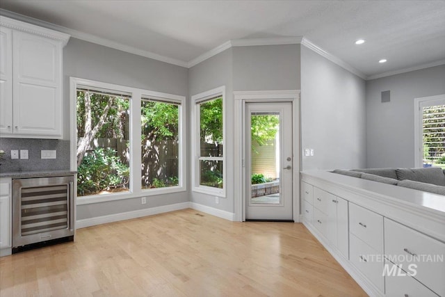 kitchen with wine cooler, light wood-type flooring, recessed lighting, white cabinetry, and crown molding