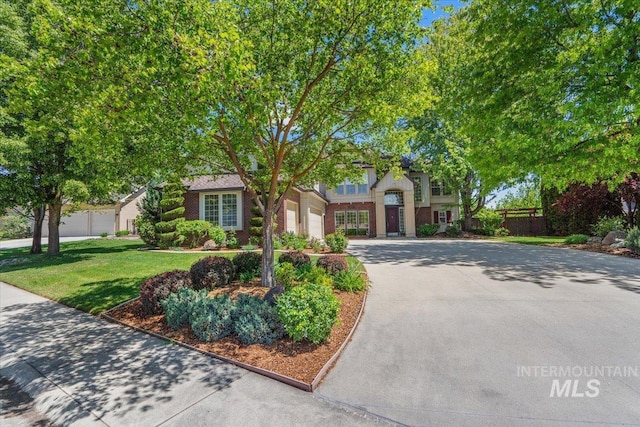 view of front facade featuring concrete driveway, a front yard, and an attached garage