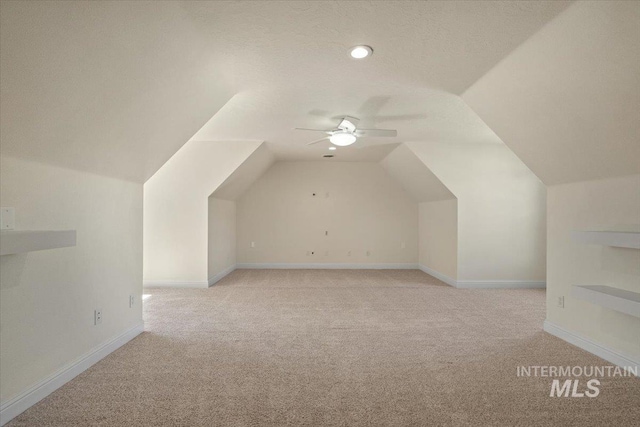 additional living space featuring light carpet, vaulted ceiling, ceiling fan, and baseboards