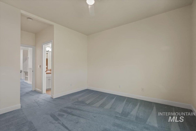 spare room featuring dark carpet and baseboards