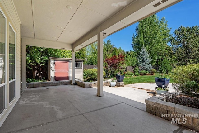 view of patio with a storage unit, an outdoor structure, and fence