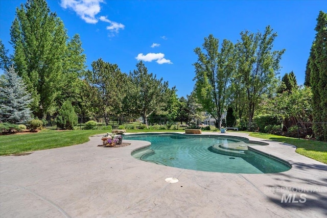 outdoor pool with a patio area and view of wooded area