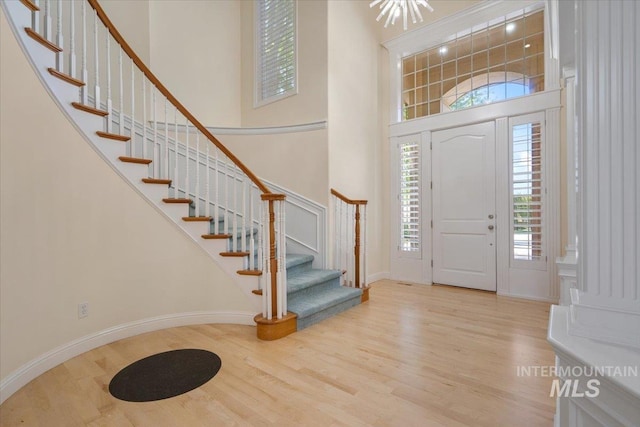 entrance foyer featuring a high ceiling, wood finished floors, stairway, and baseboards