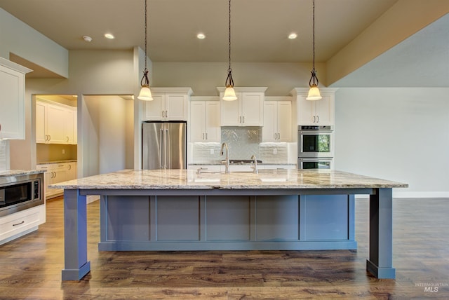 kitchen featuring stainless steel appliances, a large island with sink, dark hardwood / wood-style floors, tasteful backsplash, and white cabinets