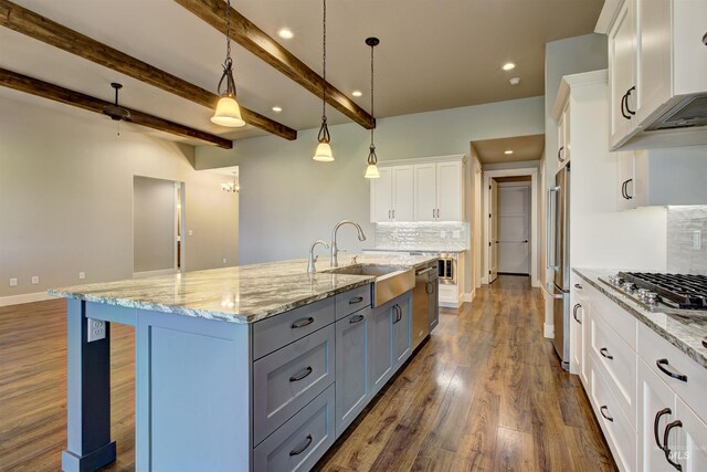 kitchen with sink, an island with sink, tasteful backsplash, white cabinetry, and pendant lighting