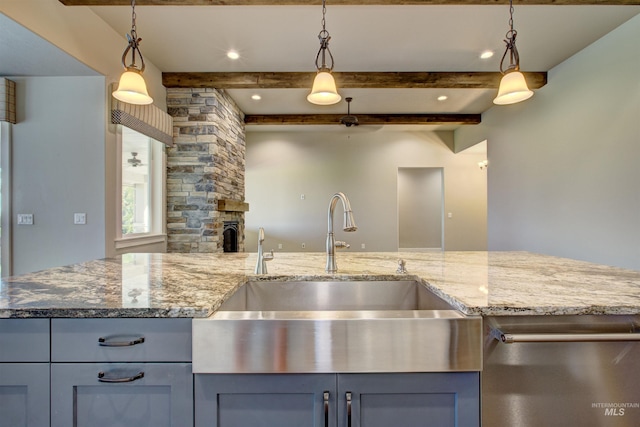 kitchen with decorative light fixtures, stone counters, sink, beamed ceiling, and a stone fireplace