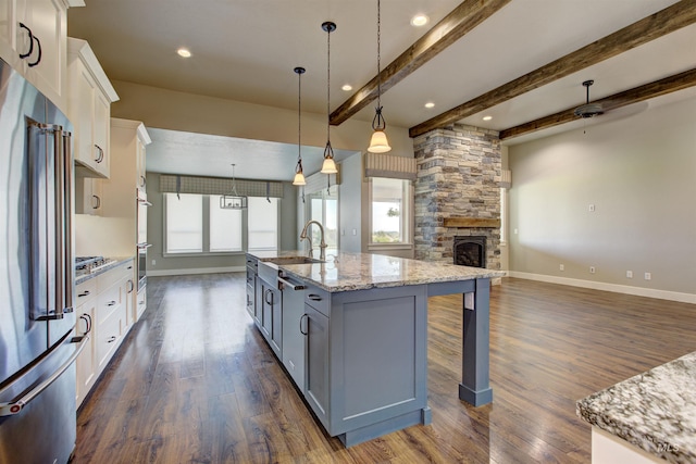 kitchen with a center island with sink, white cabinetry, dark wood-type flooring, and hanging light fixtures