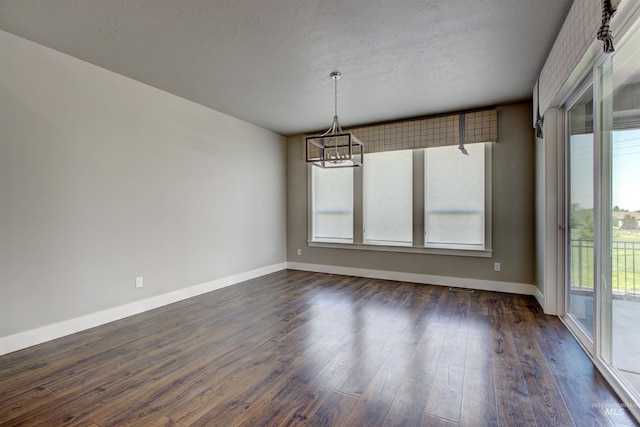 unfurnished room featuring a textured ceiling, a notable chandelier, dark wood-type flooring, and a healthy amount of sunlight