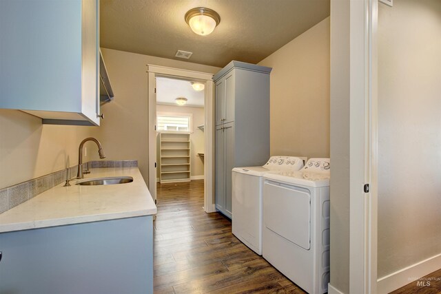 laundry room with sink, washing machine and dryer, cabinets, and dark hardwood / wood-style floors