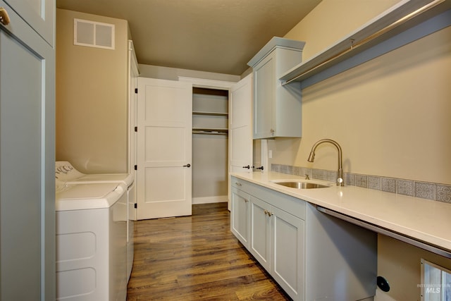 laundry area with dark hardwood / wood-style floors, sink, washing machine and clothes dryer, and cabinets