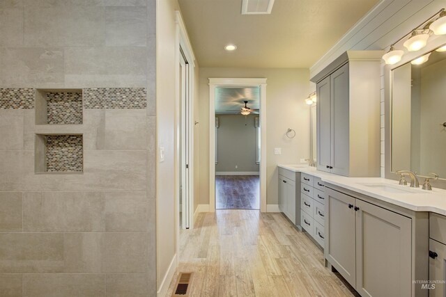 bathroom featuring ceiling fan, double vanity, and wood-type flooring