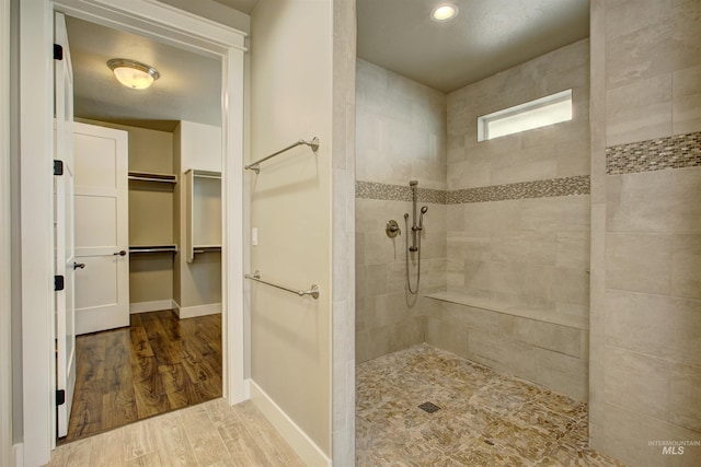 bathroom featuring hardwood / wood-style floors and a tile shower