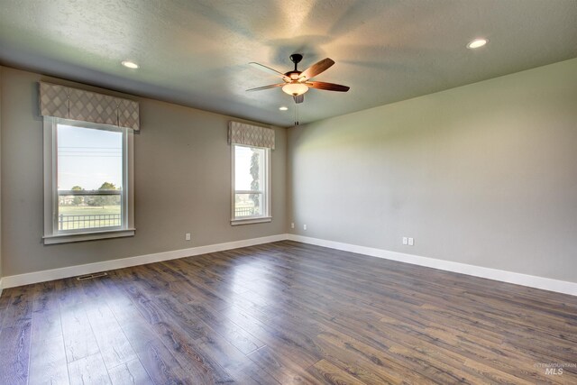 unfurnished room with plenty of natural light, ceiling fan, and dark hardwood / wood-style flooring