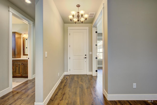 foyer entrance featuring dark wood-type flooring and an inviting chandelier