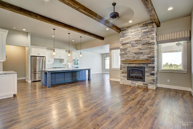 kitchen featuring hardwood / wood-style floors, backsplash, a stone fireplace, ceiling fan, and stainless steel appliances