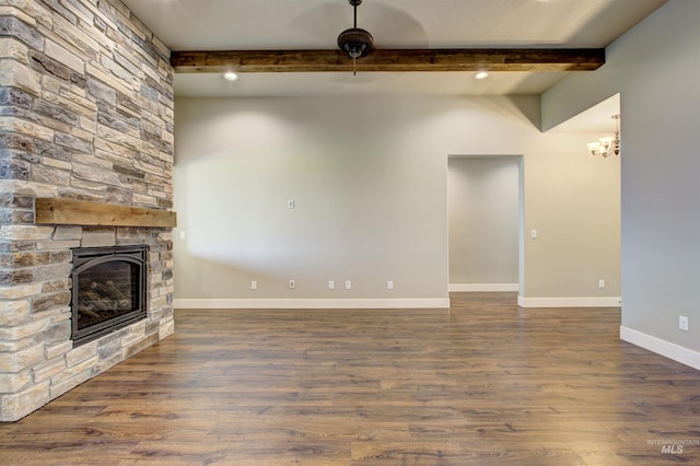 unfurnished living room with beam ceiling, hardwood / wood-style floors, a chandelier, and a stone fireplace