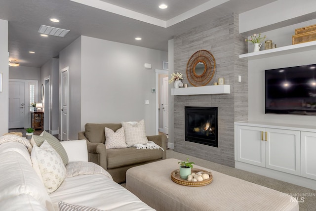 living room with a tiled fireplace, recessed lighting, and visible vents