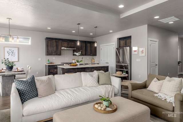 living room with a notable chandelier, visible vents, and recessed lighting