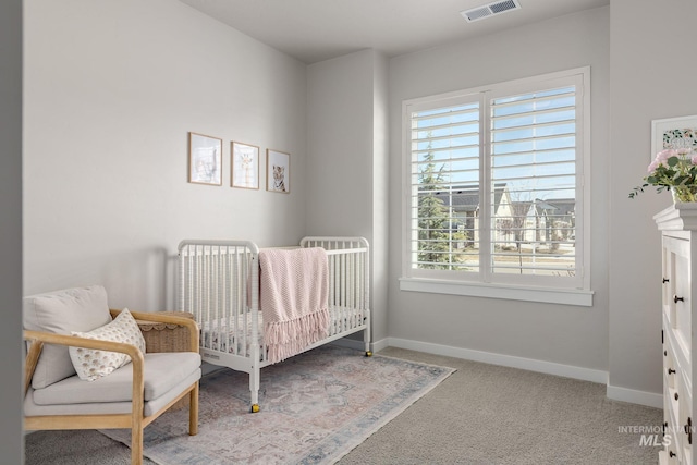 carpeted bedroom featuring visible vents, a nursery area, and baseboards