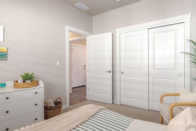 bedroom featuring visible vents, a closet, and light carpet