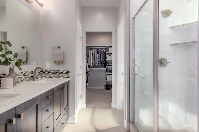 full bathroom with a spacious closet, backsplash, a shower stall, double vanity, and a sink