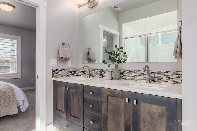 ensuite bathroom featuring a shower stall, visible vents, tasteful backsplash, and a sink