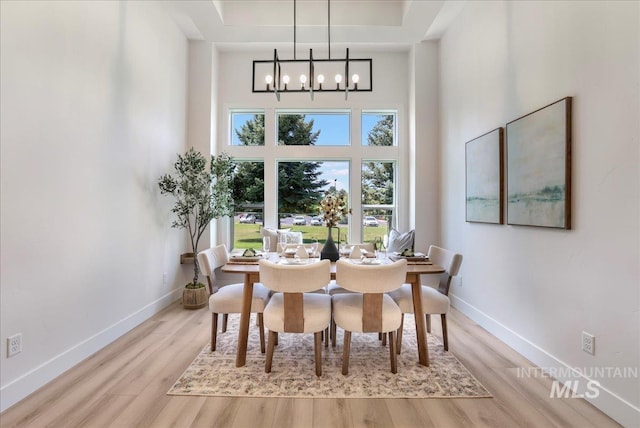 505 Stonehedge Loop, Twin Falls, ID 83301 - dining room featuring a chandelier, a towering ceiling, wood finished floors, and a tray ceiling
