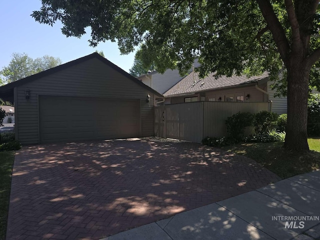 view of front facade with a garage, decorative driveway, fence, and a gate