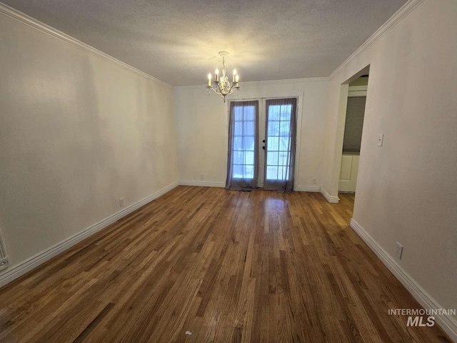 empty room with a textured ceiling, ornamental molding, dark hardwood / wood-style floors, and a chandelier