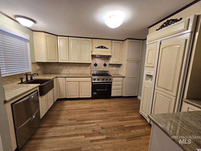 kitchen featuring sink, dark wood-type flooring, appliances with stainless steel finishes, tasteful backsplash, and light stone countertops