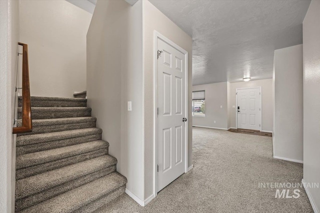 stairway with a textured ceiling and carpet