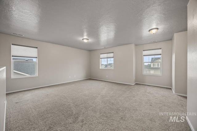 carpeted empty room featuring a textured ceiling