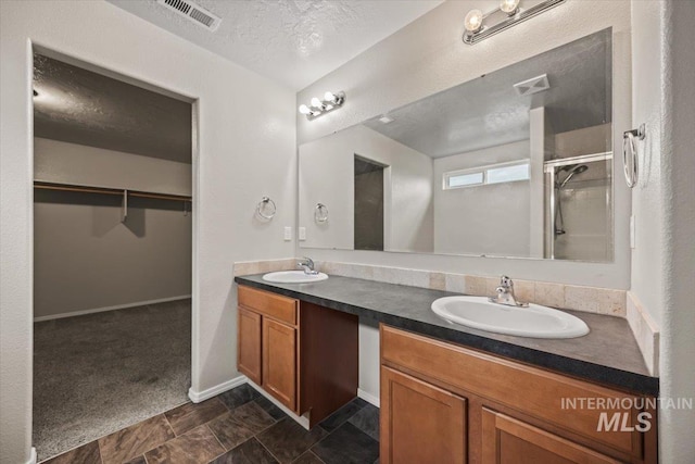 bathroom featuring vanity, a shower with shower door, and a textured ceiling