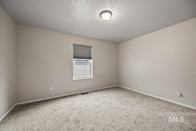 carpeted empty room featuring a textured ceiling