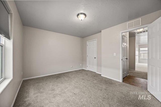 unfurnished bedroom with a textured ceiling and dark carpet