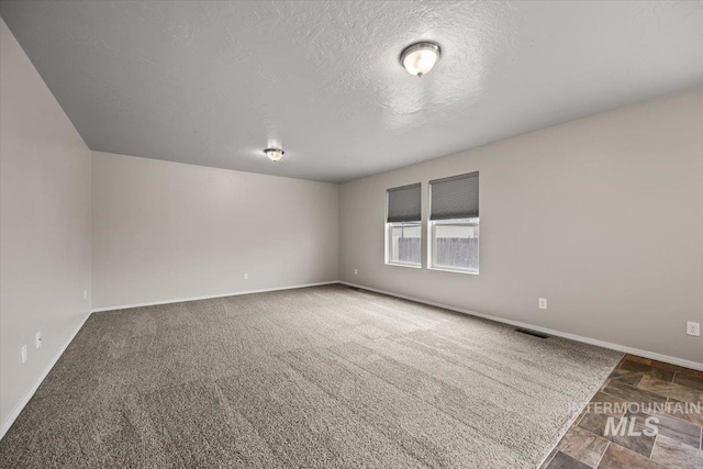 spare room featuring a textured ceiling and carpet