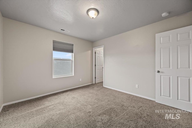 carpeted spare room with a textured ceiling