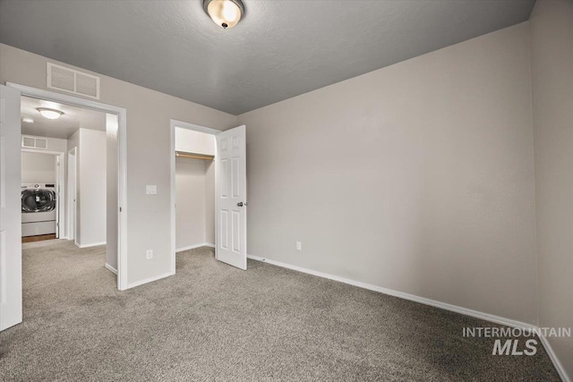 unfurnished bedroom with a closet, washer / clothes dryer, carpet floors, and a textured ceiling