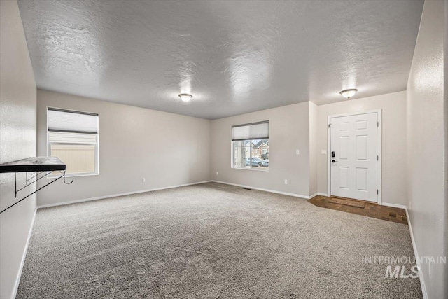 unfurnished living room featuring carpet and a textured ceiling