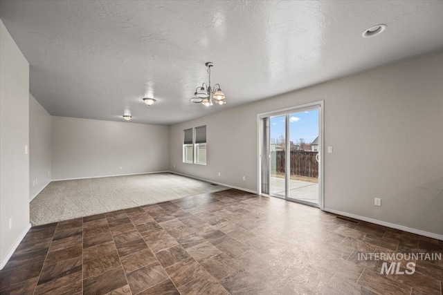 unfurnished room with a textured ceiling and a chandelier