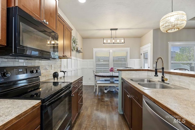 kitchen featuring black appliances, a sink, tasteful backsplash, a chandelier, and dark wood-style flooring